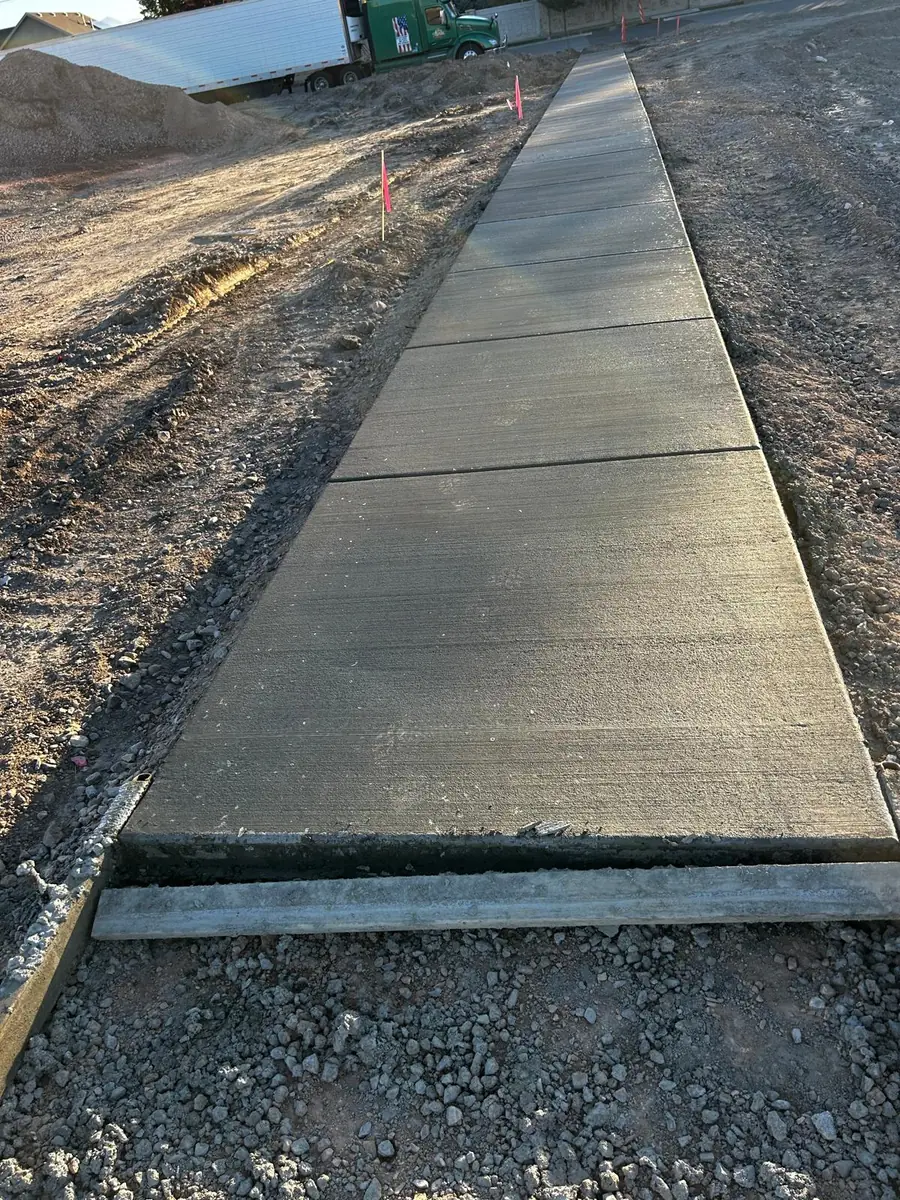 Finished concrete path alongside an open worksite