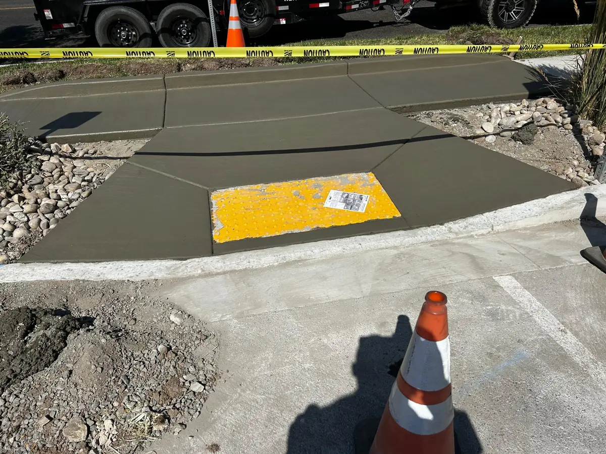Concrete curb ramp with a yellow tactile warning panel