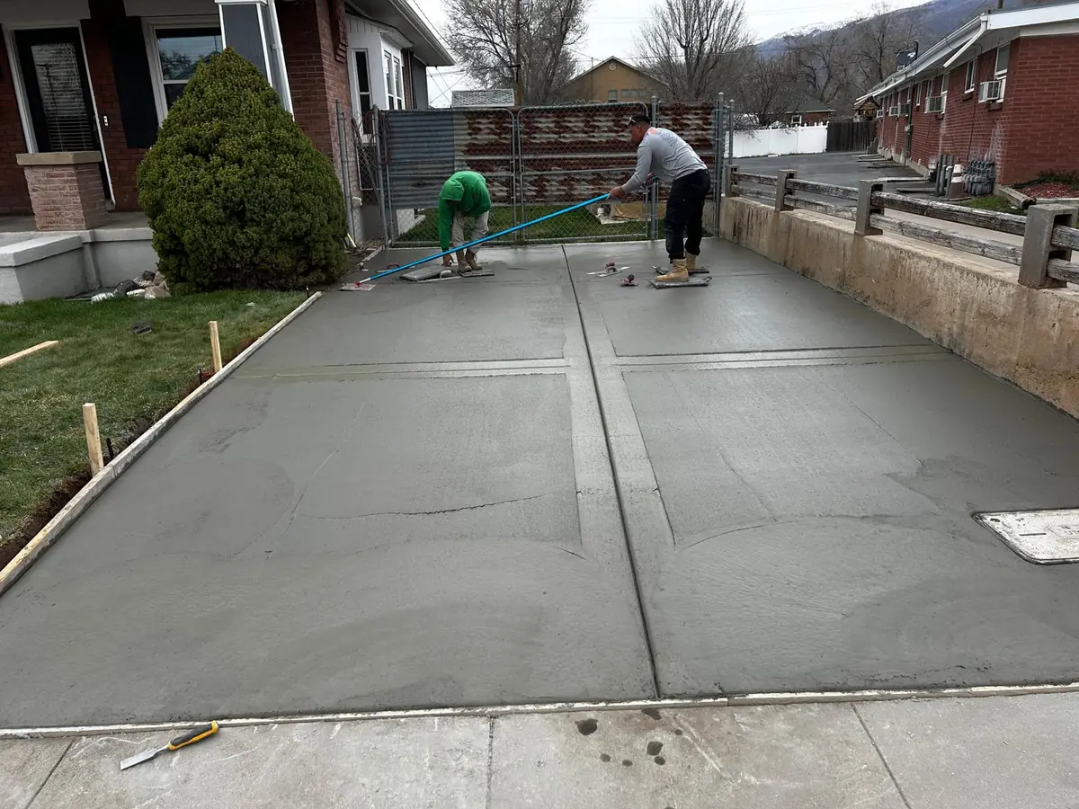 Crew members working on a newly placed concrete driveway