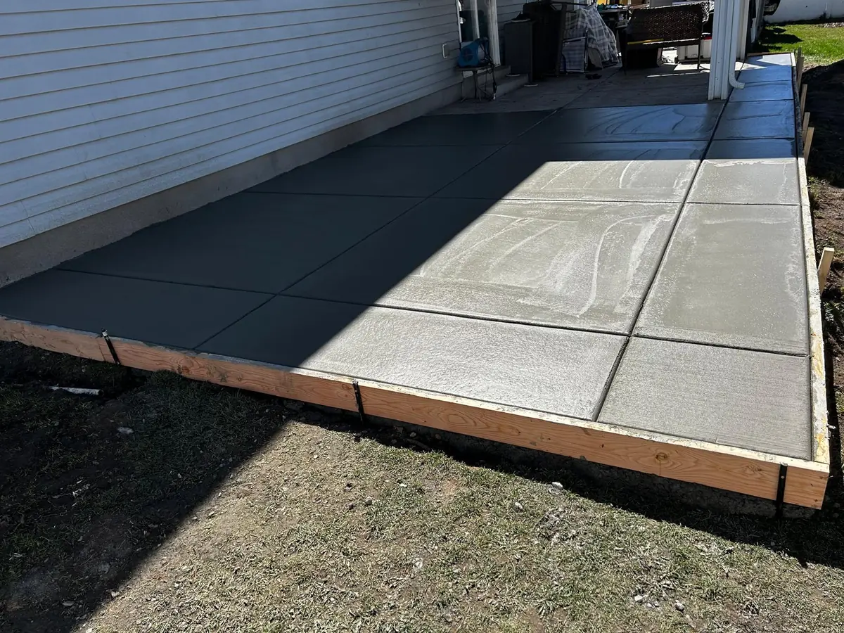 Finished backyard concrete patio beside a covered porch