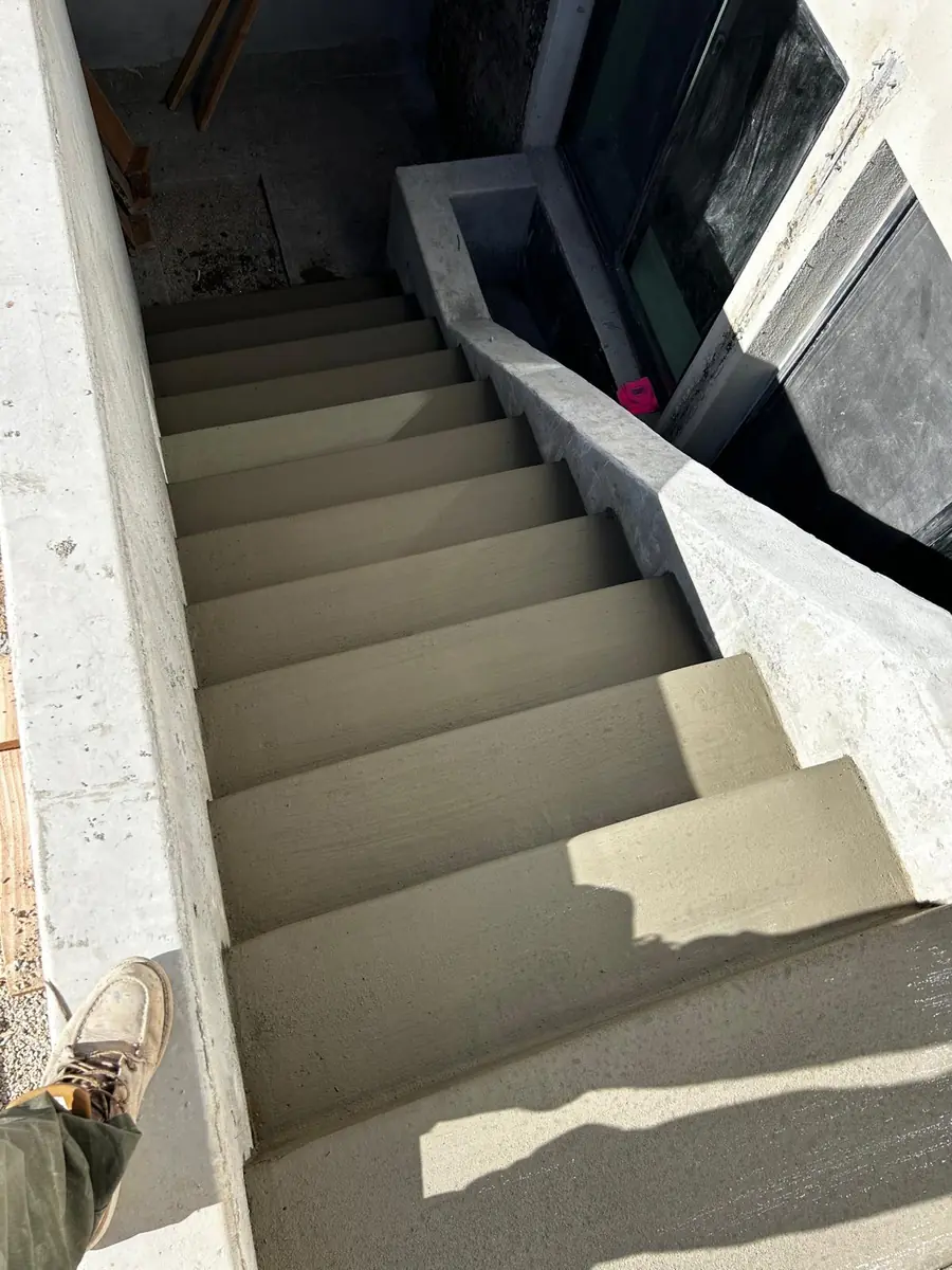 Concrete basement entry stairs beside a home