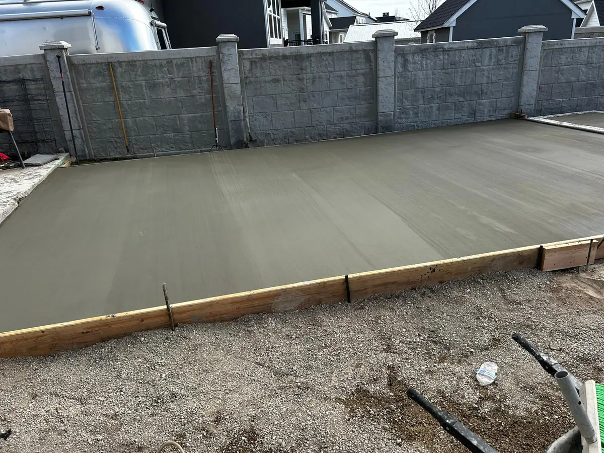 Concrete slab with straight forms beside a fenced yard